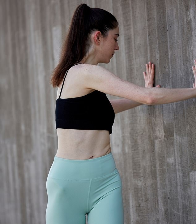 Ms Hunt shows us how to do the seated twist. This move can be done in your office chair or by pushing against a wall as Ms shows in this image